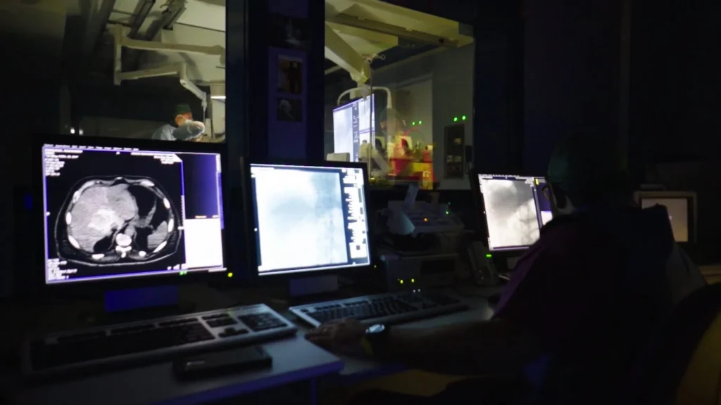 Specialista che analizza immagini di scintigrafia post-trattamento per valutare la distribuzione delle microsfere.